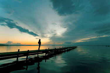 A woman on a dock looking up to the sky.