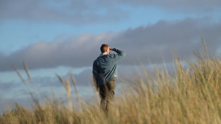 As global winds of change stir uncertainty, we must stay alert to the shifting tides of world events—and recognize God's call to prepare our hearts for what lies ahead. A man walking in a field looking at the clouds.