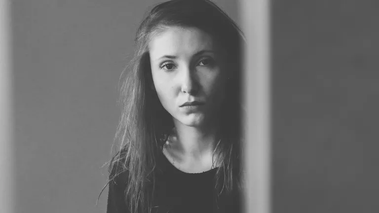 I thought I could fix him with my advice and suggestions. I was in denial and trying to control what was not mine to control; I was in God’s way, and I had a lot to learn myself. A young woman looking from behind an edge of a wall.