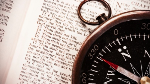 Compass laying on top of a Bible opened to Exodus 20 - where the 10 Commandments are listed.