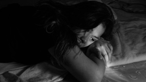 A woman laying on a bed looking depressed.