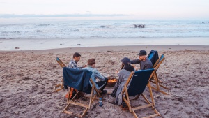 A group of friends around a campfire on the beach.