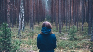 A young woman looking into a forest.