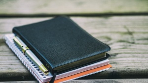 Bible, notebook and pen on a table.