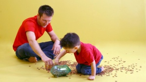 A father and son counting pennies from a glass jar.