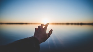 A hand reaching out over water.