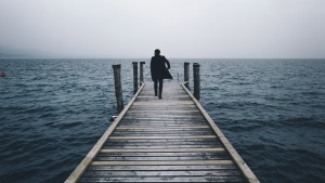 A man walking on a pier going out into the water.