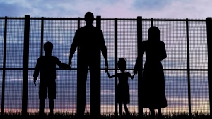 A family of four looking through a tall fence.