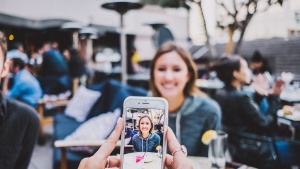 A woman taking a photo of another women with a smartphone.