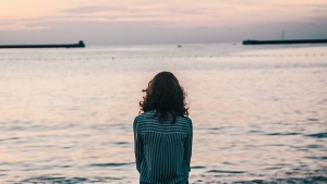 A woman sitting by a large body of water.