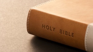 A brown Holy Bible on a table.