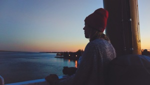 A woman looking out over a body of water at sunset.