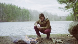 A man sitting by a campfire.