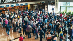 Airport travelers standing in line to go through immigration customs.