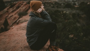 A young woman sitting on a boulder.