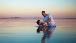 A man putting another man under water.