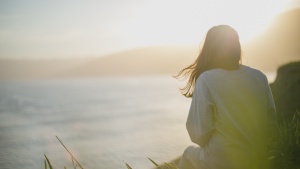 A woman sitting watching the sunset.