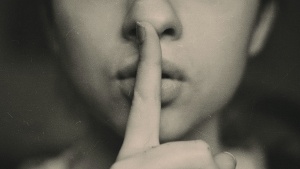 Picture of a person with finger over their lips.