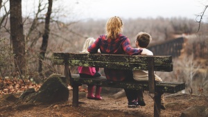 Photo of mother with two children on a bench.