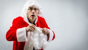 A man putting on a Santa Claus costume.