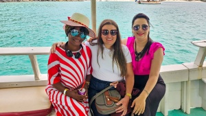 three ladies sitting in front of a railing with water in the background