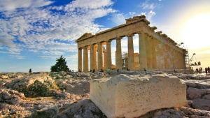 Ancient ruins of the Parthenon with tourists by the structure and a large block of stone in the foreground