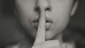 a woman with a finger to her lips in a gesture for silence