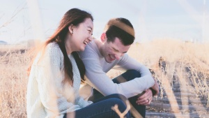 a man and a woman seated next to one another and laughing