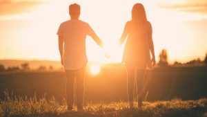 a couple holding hands silhouetted against the sunset