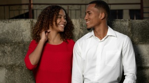 a man and woman standing against a stone wall