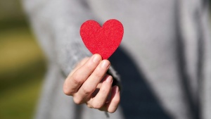 a woman's hand holding up a red paper heart