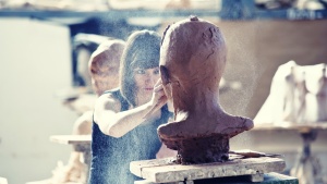 A woman sculpting a clay head.