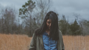 a woman with her head down standing in a field