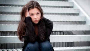 A women sitting on steps holding her head.