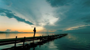 A woman on a dock looking up to the sky.