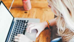 A woman typing on a Mac laptop.