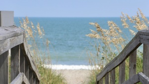 a wooden walkway leading towards the sand and ocean