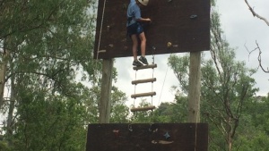 Youth climbing a rope ladder and rock wall