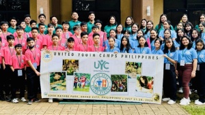 a large group of people standing outside in matching shirts with a UYC banner