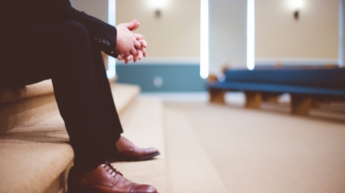 a man wearing a suit sitting on indoor steps