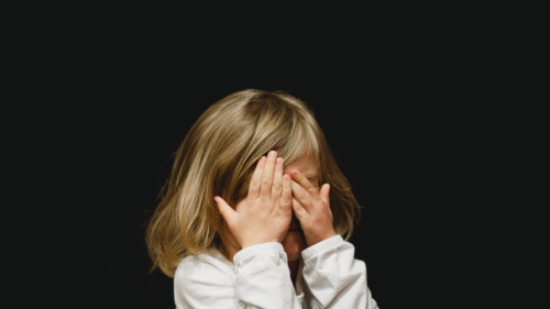 a child covering her face with her hands