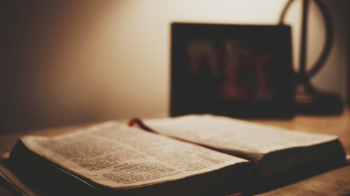 an open bible on a table in lamplight