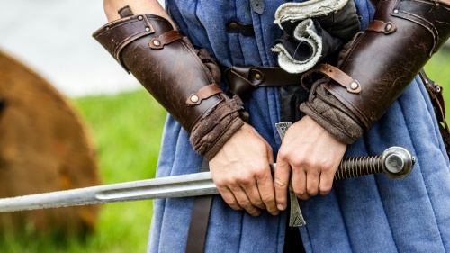 a person dressed in Medieval clothing and protective gear, holding a sword