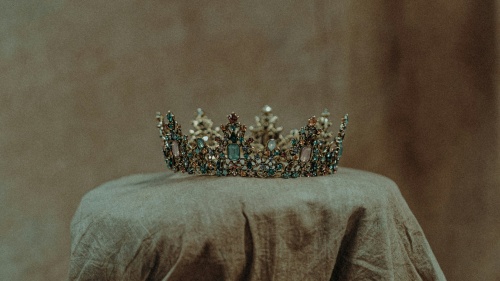 a crown displayed on a cloth-covered pedestal in a dimly-lit room