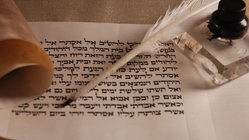 a scroll with Hebrew writing, a feather pen, and an inkwell