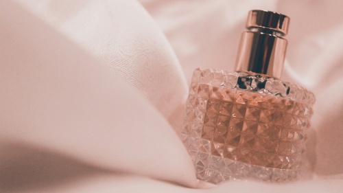 a glass bottle of perfume swathed in pink material