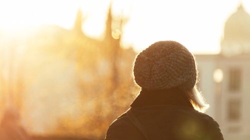 silhouette of a woman with a knit cap outdoors surrounded by golden sunlight