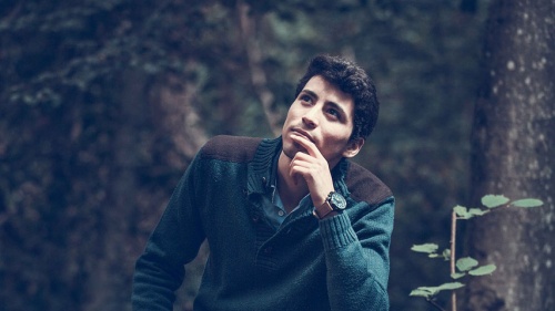 a man looking towards the sky amidst trees in the forest