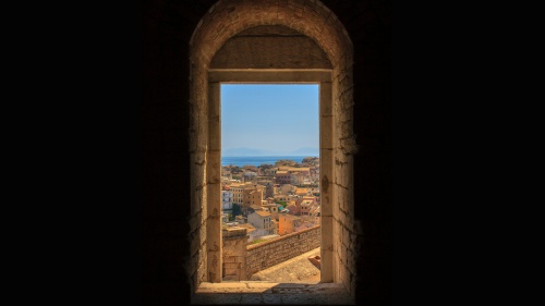 a door framed with a brick archway that looks out over a historic city