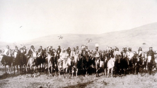 A large group of men on horseback with mountains in the background. In the front center of the group can be seen Chief Joseph, White Bird and Looking Glass.